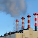 Industrial facility with smokestacks emitting gases, illustrating what are fugitive emissions and their environmental impact
