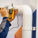 Technician using a handheld device for gas monitoring, ensuring safety and compliance in an industrial setting.