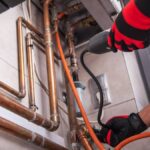 A technician uses a gas leak detector to inspect copper pipes for leaks, ensuring safe and reliable gas storage solutions.