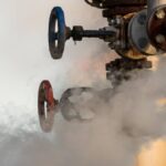 Close-up of a leaking gas valve emitting steam, illustrating the urgency of knowing who to call for gas leak situations.