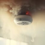 Close-up of a ceiling-mounted gas detector surrounded by smoke, emphasizing the importance of gas detector calibration.