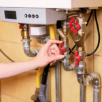 Person adjusts red gas valve on a gas system, illustrating inspection steps in gas safety audits for compliance.